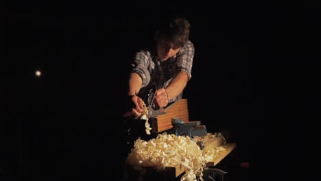 Wide-shot-of-young-carpenter-hand-planing-pine-timber,-Dramatic-hard-light