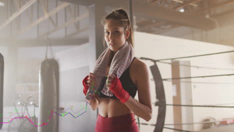 fitness data tracking animation over woman with towel in boxing gym