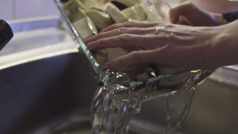 tomas en cámara lenta lavando berenjenas crudas, cerrando el grifo y lavando el agua de las verduras