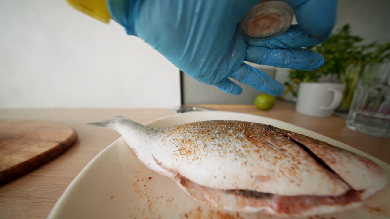 Close-up of Hand Seasoning Raw Fish with Salt in Kitchen