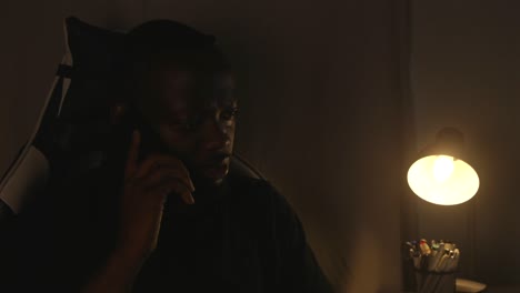 black male receiving bad news over the phone at home