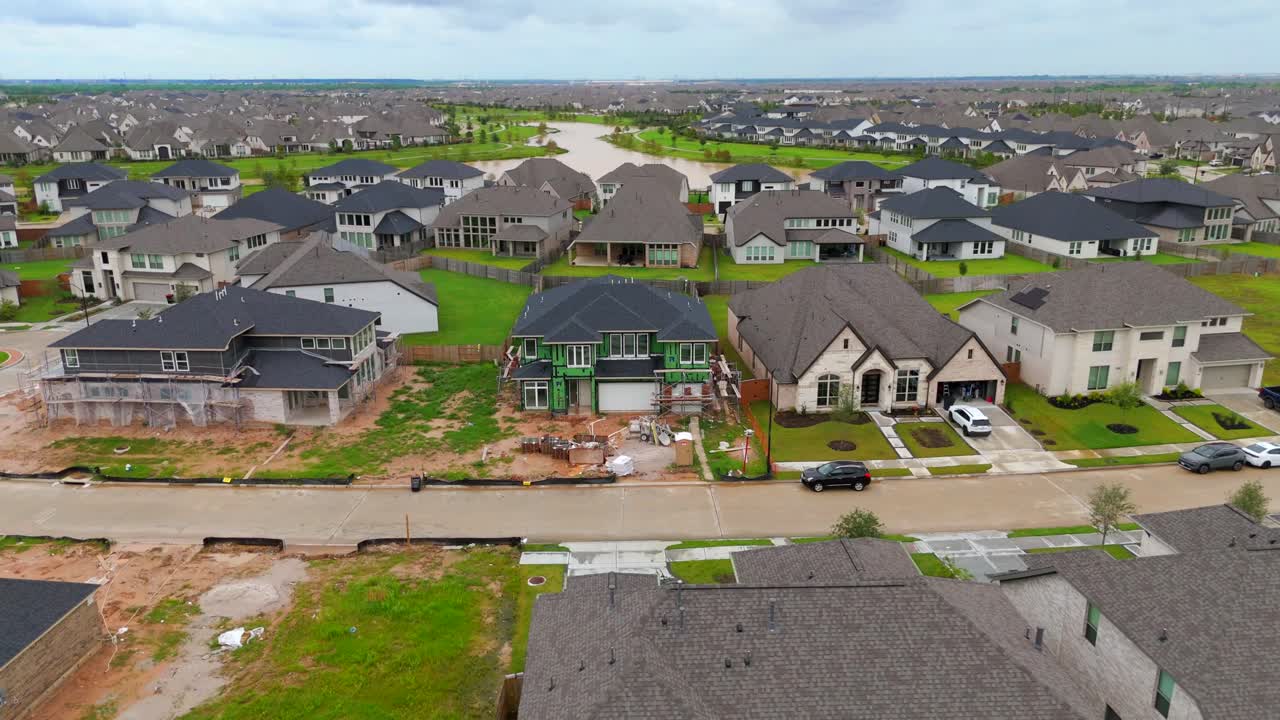 An aerial recording of a house that is under construction in a suburban neighborhood