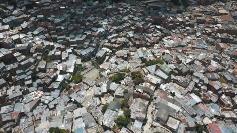 Drone-aerial-view-of-houses-in-poor-neighborhood-revealing-mountains-in-Comuna-13-slums,-Medellin,-Colombia