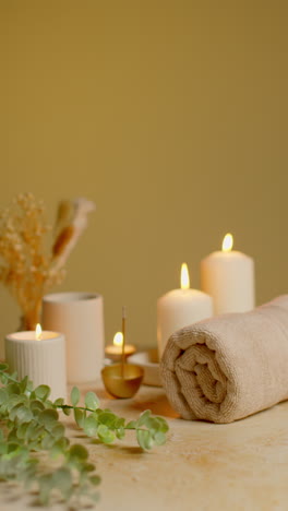 vertical video still life of lit candles with dried grasses incense stick and soft towels as part of relaxing spa day decor 1