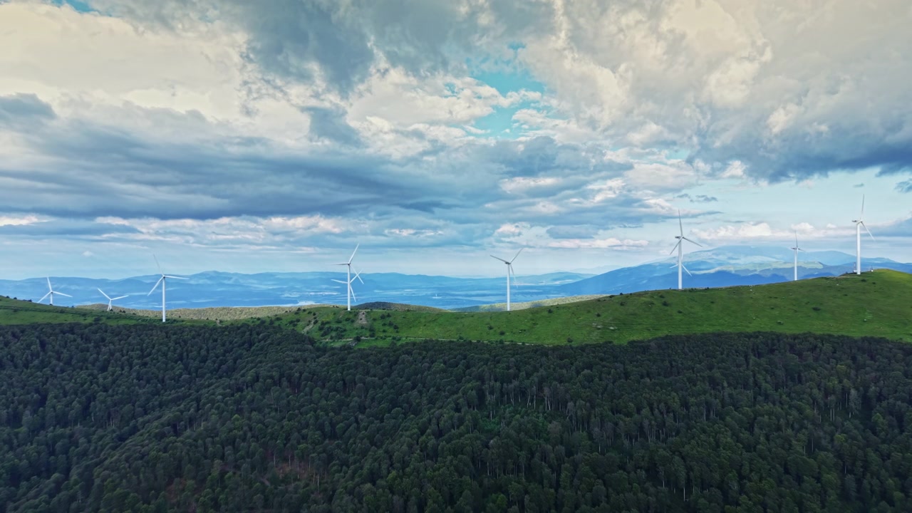 Colline verdi e turbine eoliche si stagliano contro un cielo nuvoloso in un paesaggio suggestivo che mostra la natura e le fonti di energia rinnovabile.