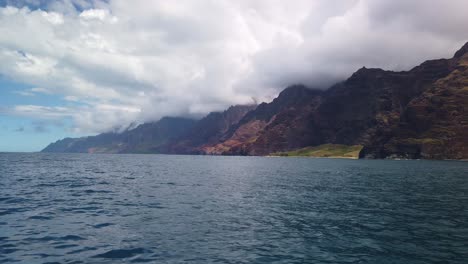 Gimbal-wide-shot-from-a-boat-of-the-beautiful-Na-Pali-Coast-with-spinner-dolphins-in-the-ocean-in-Kaua'i,-Hawai'i