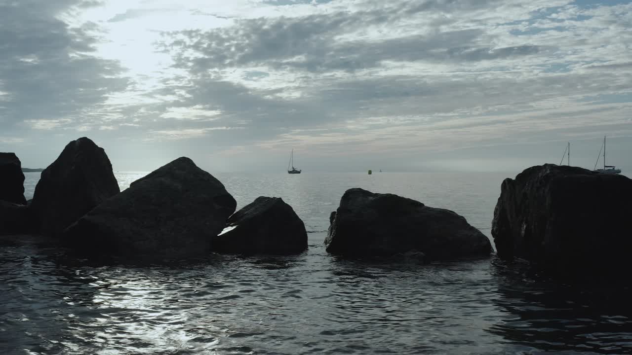 바다에 있는 바위들의  ⁇ 은 아침  ⁇ 빛 앞에 그려져 있습니다.