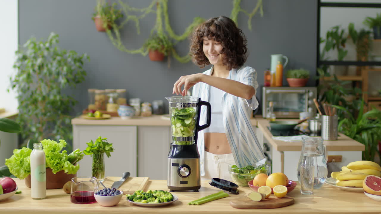 Giovane donna che prepara un frullato verde