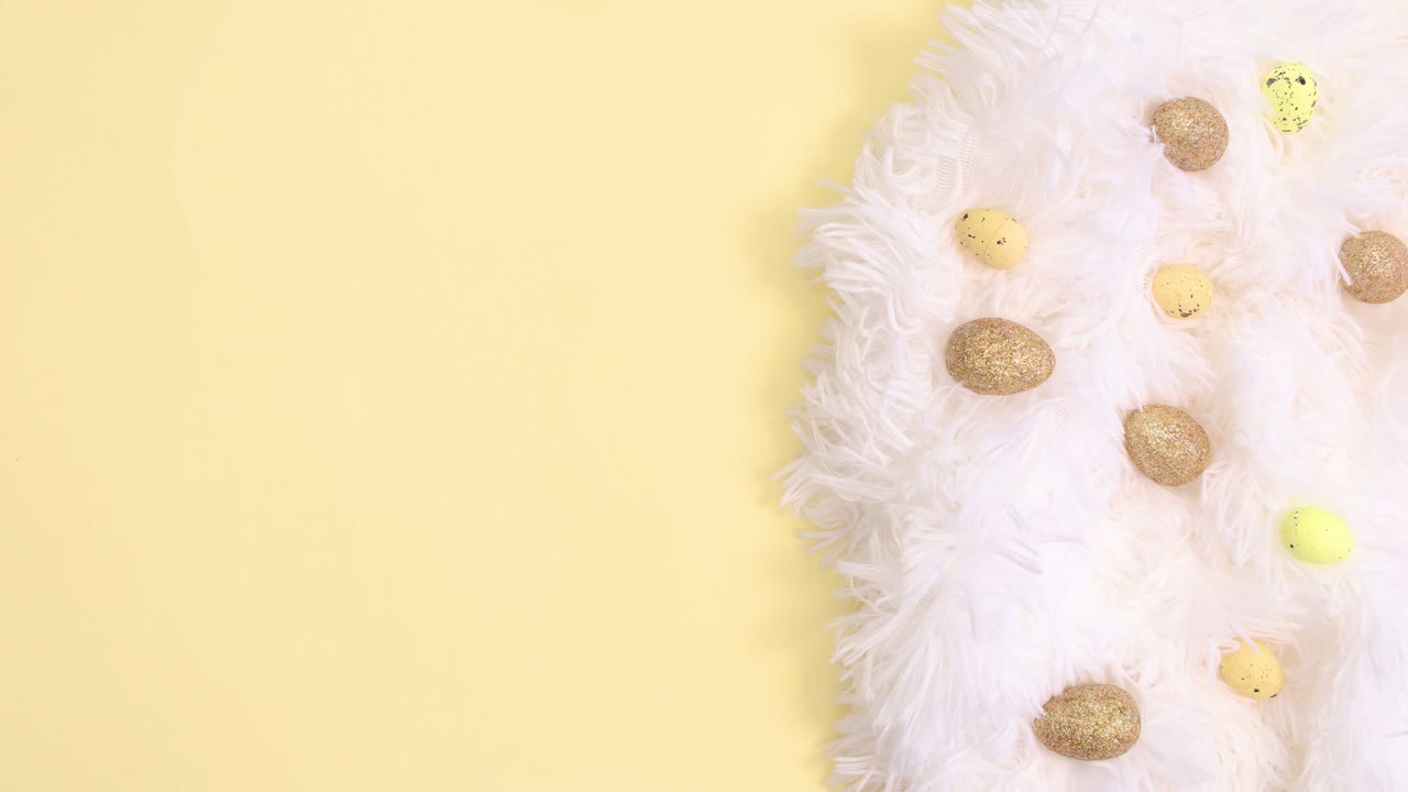 Easter white and gold decoration appear on bright yellow background. Stop motion flat lay