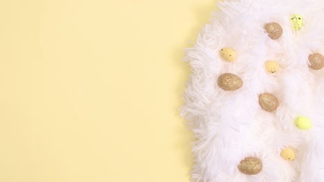 easter white and gold decoration appear on bright yellow background. stop motion flat lay