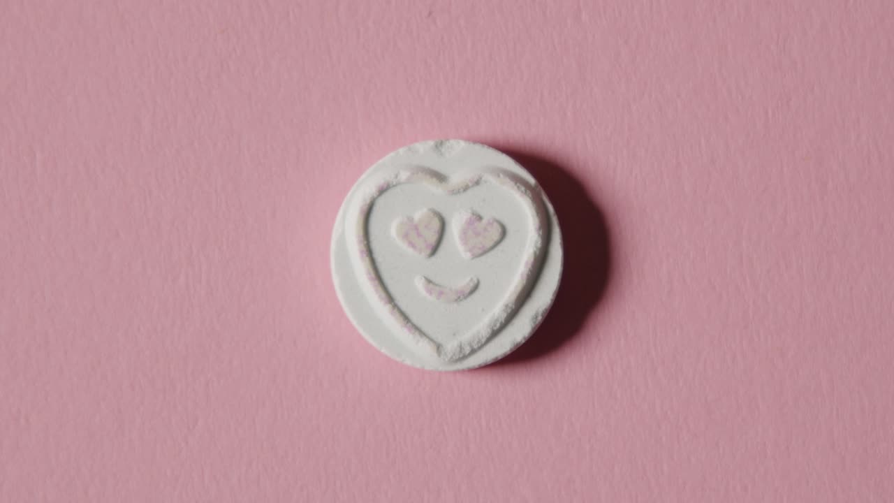 caramelo de corazón con amor emoji sobre fondo rosa