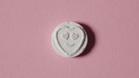 heart candy with love emoji on pink background