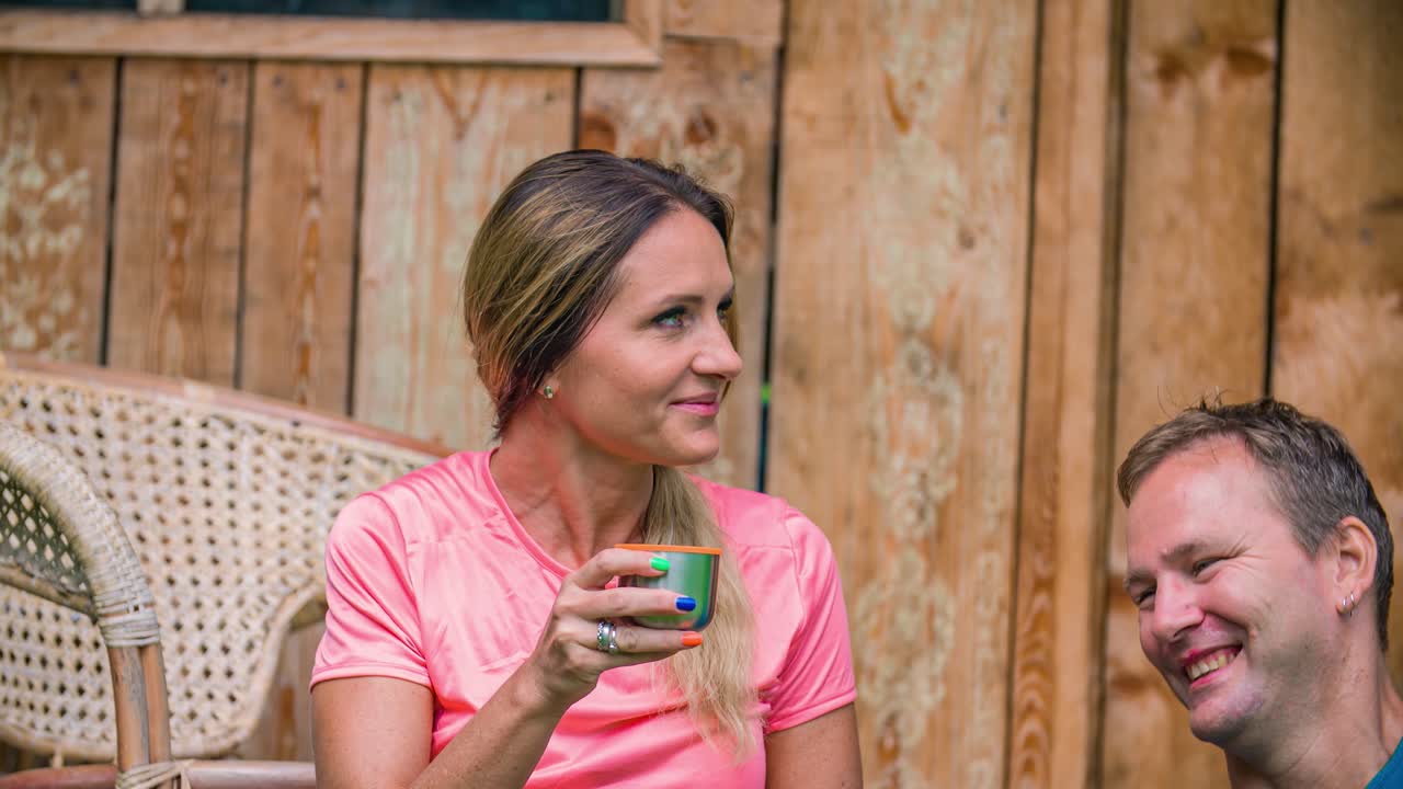 Close up of a woman sitting outside sipping a drink with a man next to her