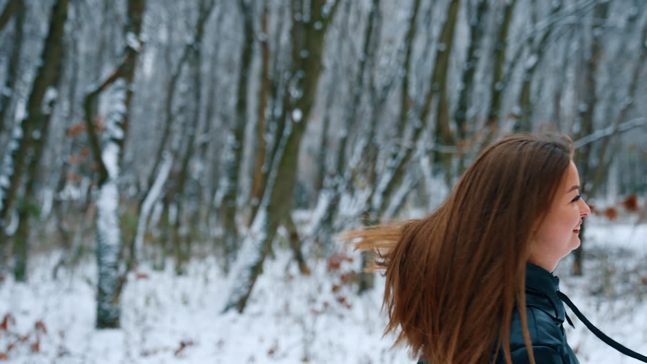 Happy smiling Caucasian lady turning and waving her hair. Woman is rejoicing her life and walk in winter park.