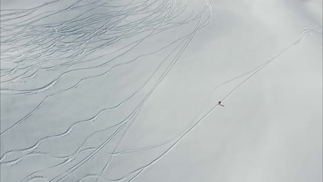 Aerial--Lone-skier-descending-on-snowy-slopes-with-trails