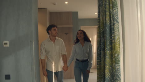 smiling couple entering hotel room. beautiful couple looking around in suite.