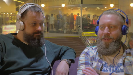 two bearded men listening to music in headphones