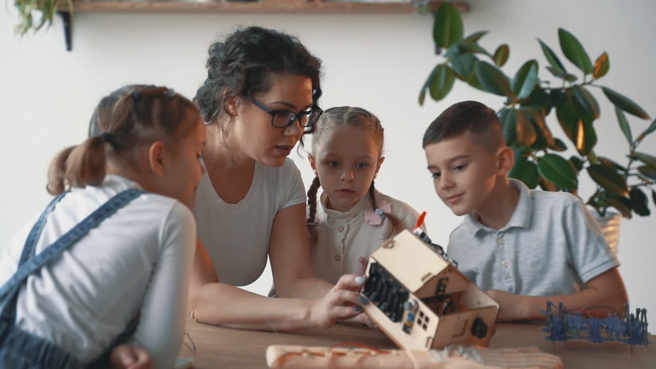 mujer ayuda a niños y niñas interesados en la ciencia y la tecnología a construir robots