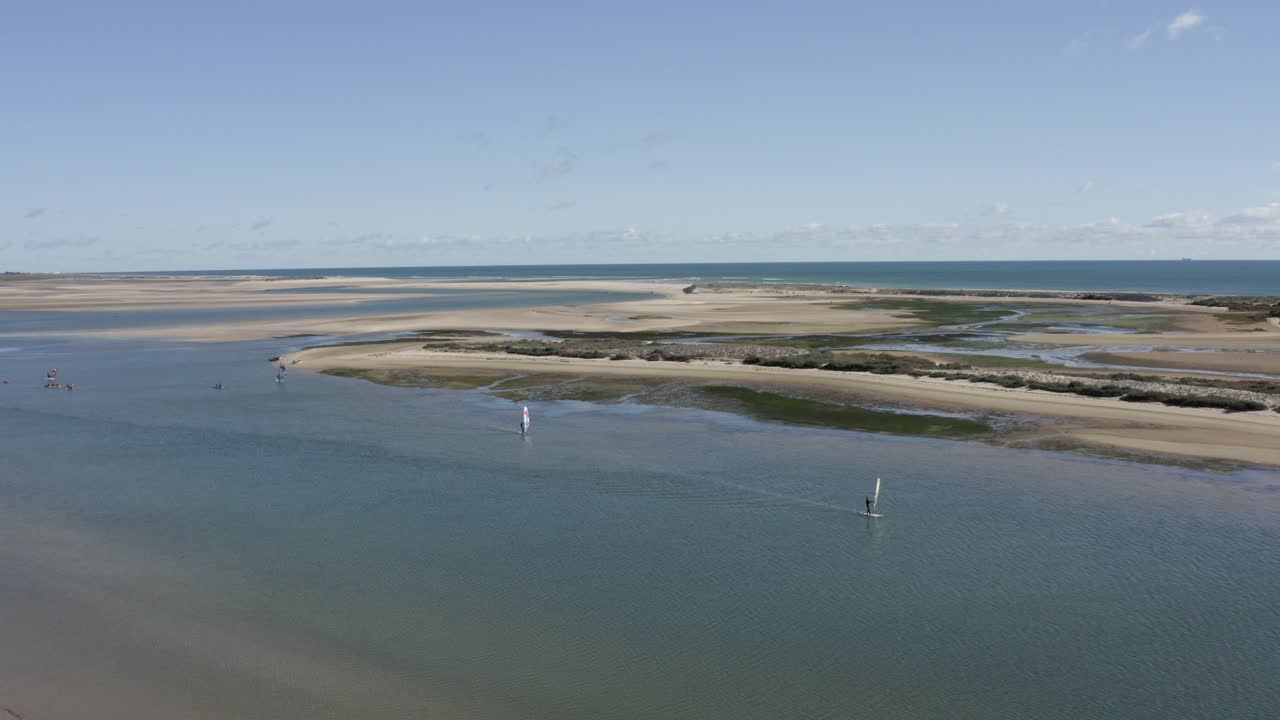 windsurfistas navegando a lo largo de una playa en ria formosa furseta, portugal