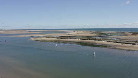 windsurfers cruising along a beach at ria formosa furseta, portugal