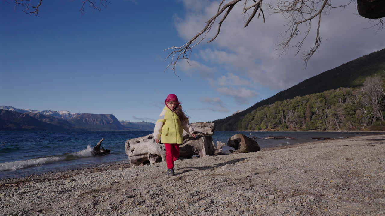 A little girl in red pants walks away from the shore at Villa Traful, Argentina