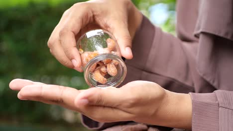 woman pouring sugared cashews from a jar into her hand