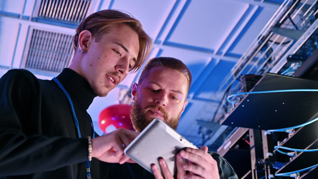 Two men analysing data in a server room