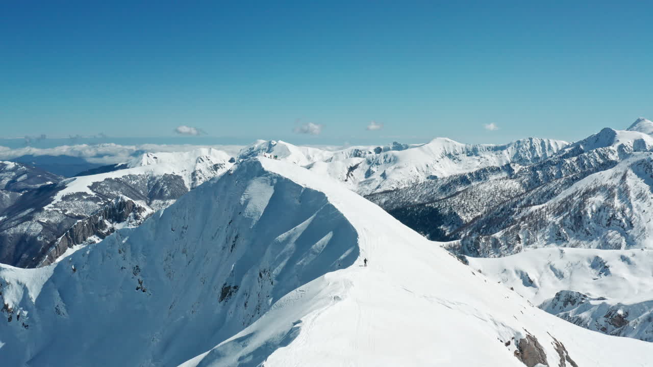Cime montuose innevate sotto un cielo azzurro e limpido, scatto panoramico in piena luce diurna.