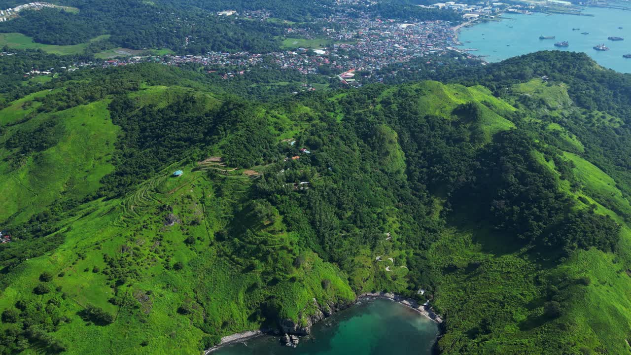 Bird’s‑eye aerial of Nagbayog View Deck in Mariveles, Bataan, capturing lush green hills, winding paths, and the dramatic coastline meeting the calm turquoise sea below