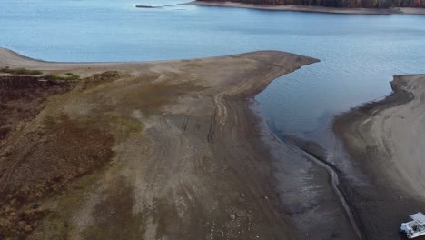 Reservoir-with-very-low-water-level,-beached-boat-in-autumn