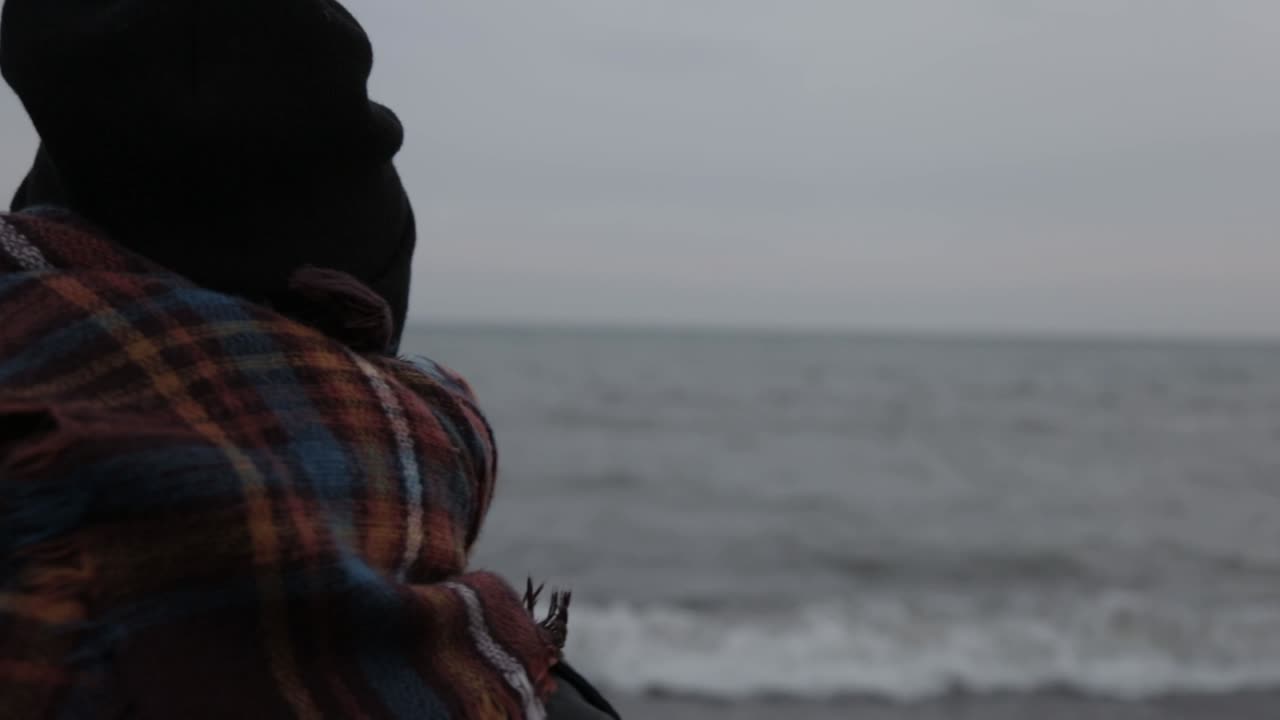 una hermosa joven sentada cerca de la costa mientras espera a alguien - toma de cerca