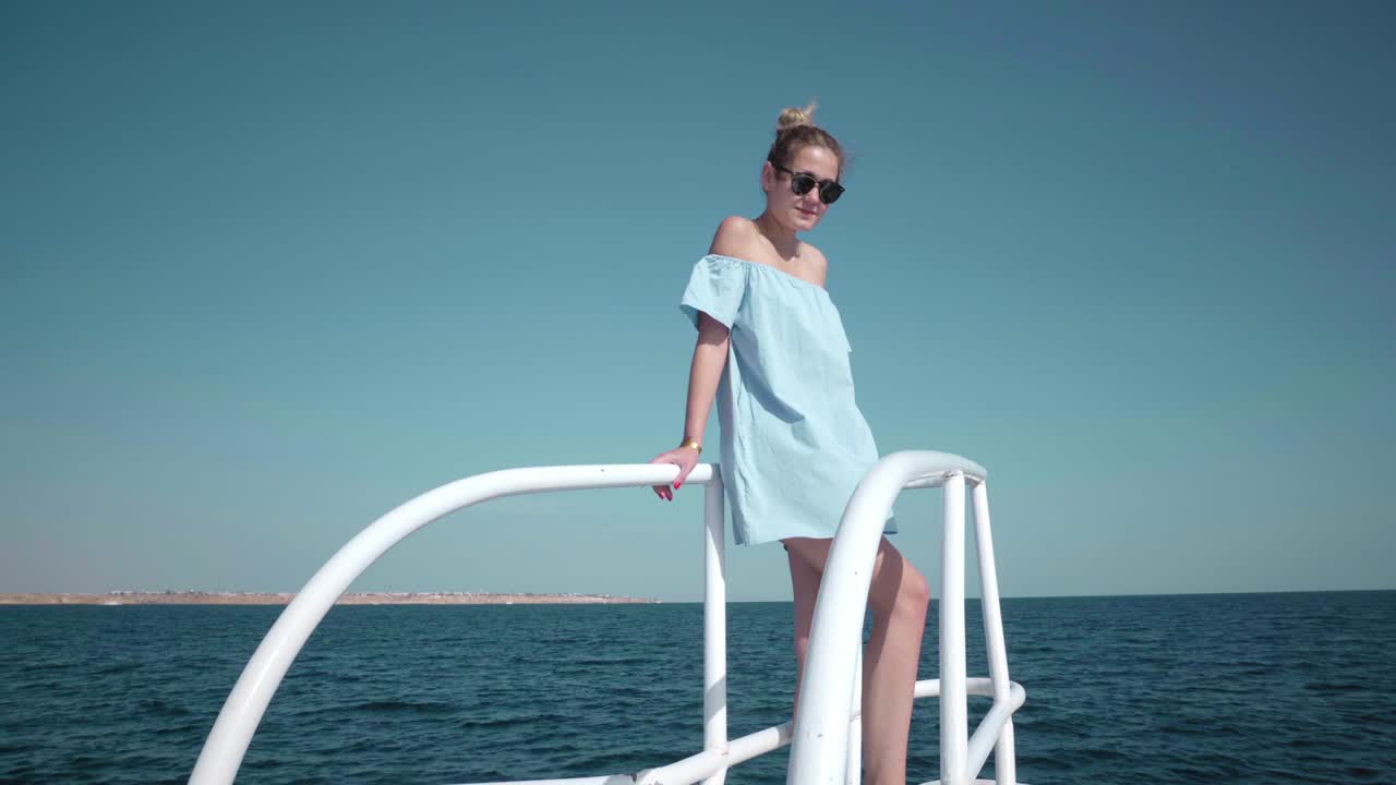 파란색 드레스와 선글라스를 입고 요트에 탑승한 젊은 섹시한 백인 여성의 초상화 - 휴가, 자유, 빛 여름의 개념 - 배경에 파란 바다