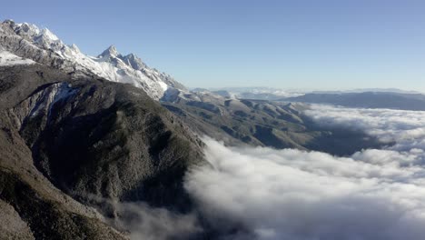 Amazing-aerial-view-of-Chinese-Jade-Dragon-Mountain-rising-above-clouds,-Yunnan