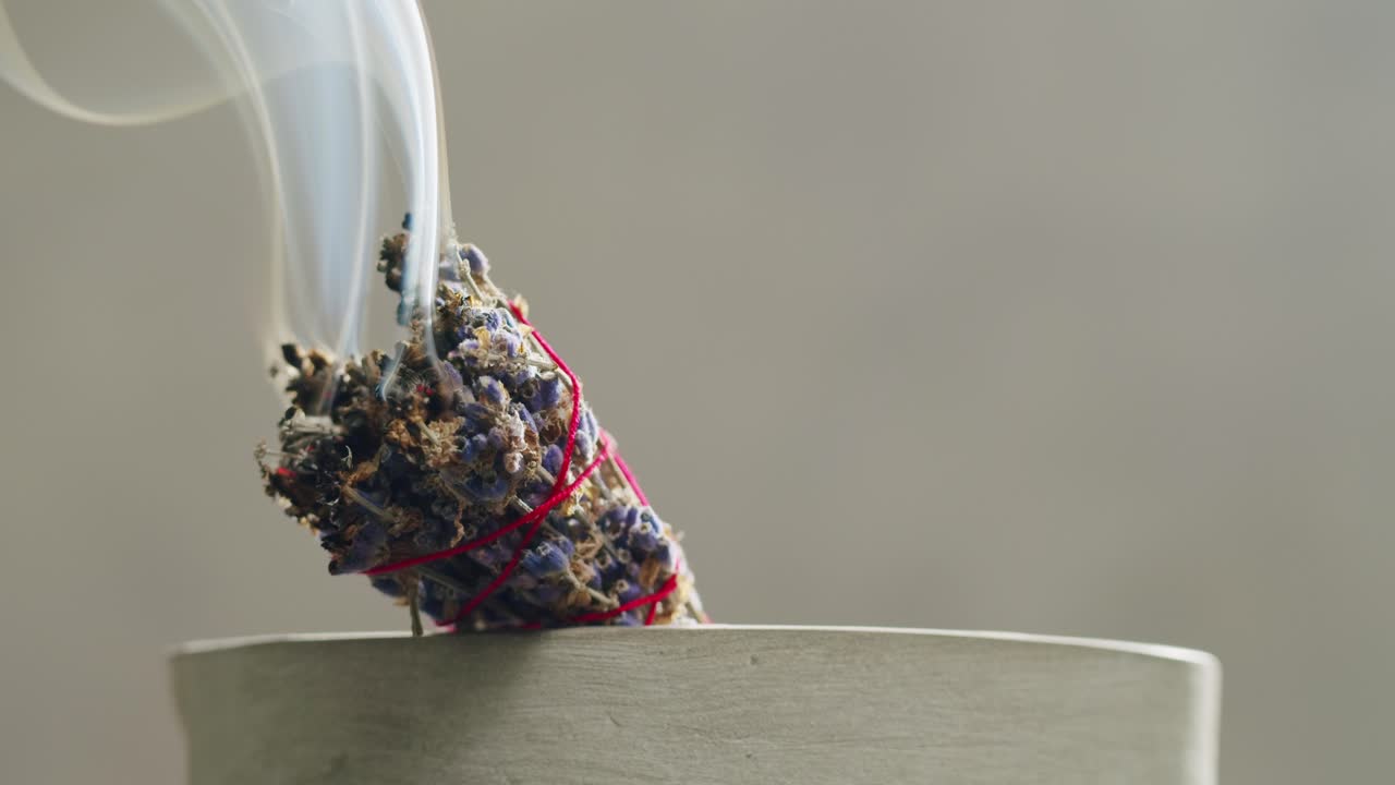 Person holding Palo Santo wood stick in hand, aromatic Palo Santo burning on black background, smoke spreading around, slow motion video clip, high quality 4k close up footage. High quality 4k footage