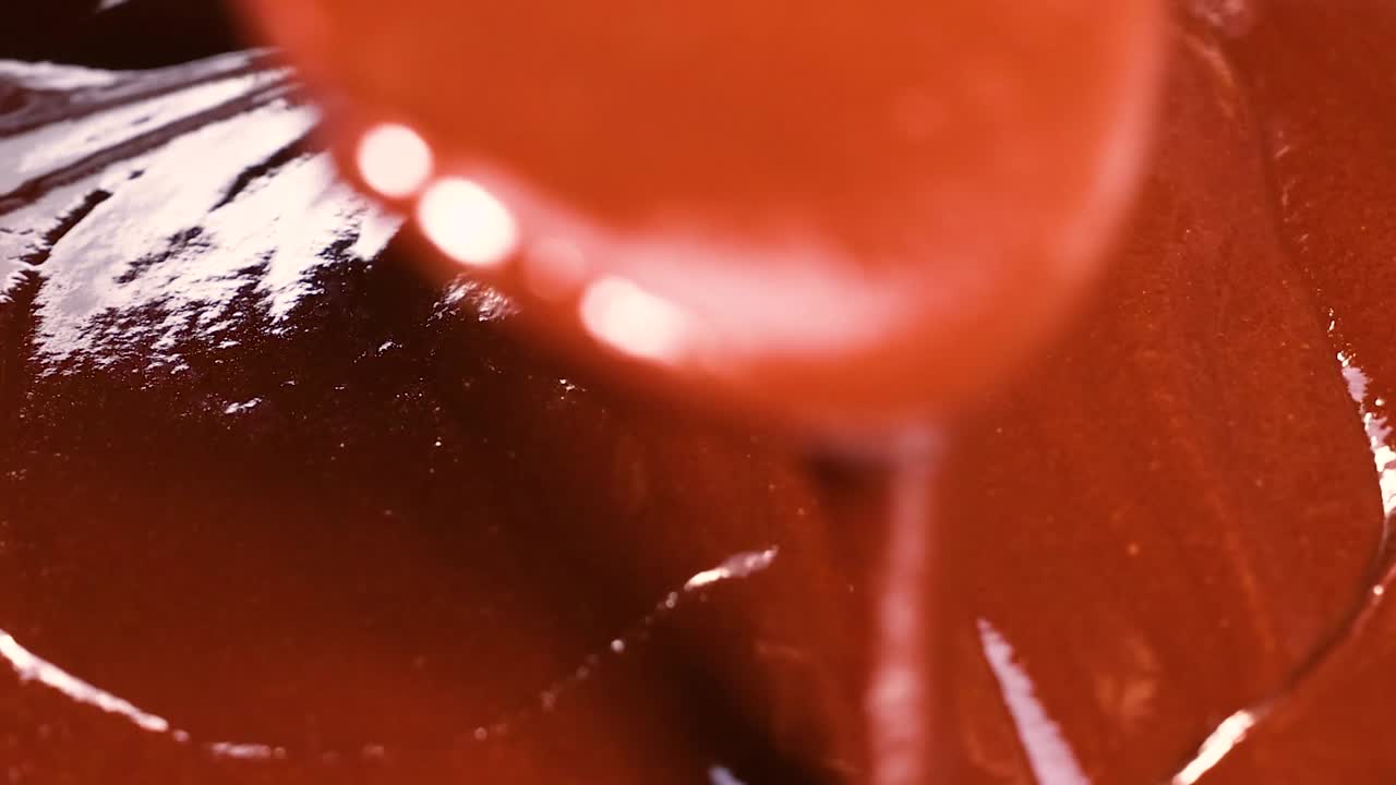 Una vista dettagliata di cioccolato ricco e lucido che scorre e si avvolge dolcemente
