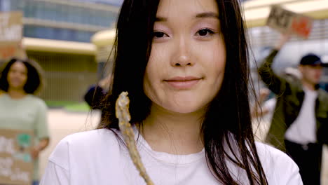 Zoom-In-Footage-Of-Young-Woman-Showing-Dead-Plant-In-A-Pot-While-The-Protesters-Shout