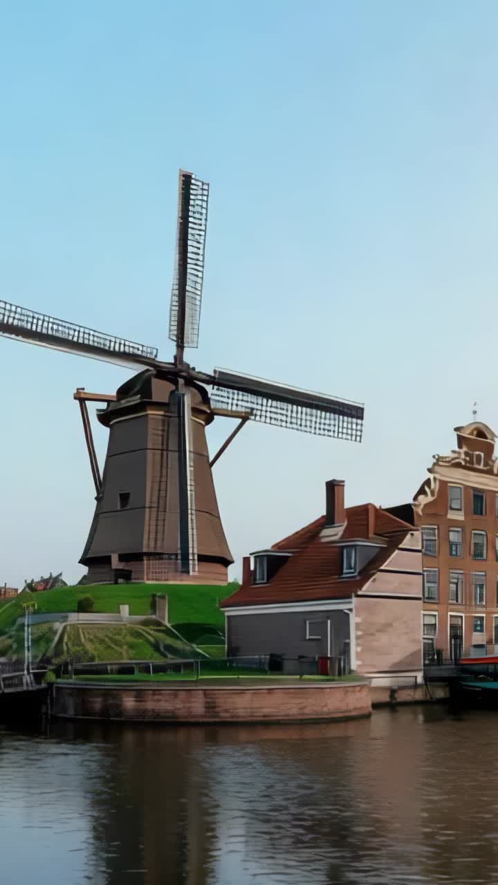 Vertical video: Peeling red-white-blue torn overlay revealing Dutch windmill by canal-side houses
