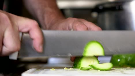 close shot of a zucchini being chopped on a white table