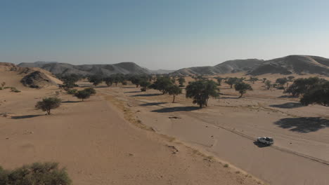 siga la toma aérea del vehículo en la carretera en el desierto en dirección a las montañas