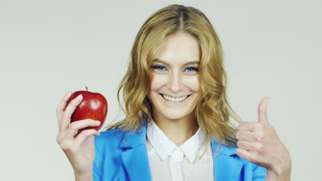 chica con manzana roja en la mano mostrando gesto de aprobación con el pulgar hacia arriba video hd