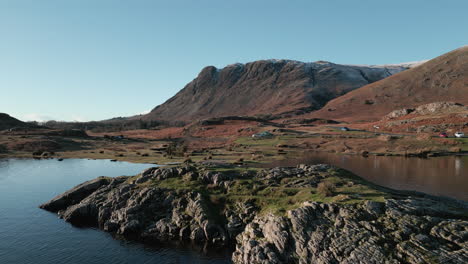 calm lake island approach with mountain in distance in winter at wasdale lake district uk