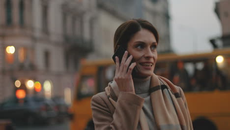 Mujer-De-Negocios-Caucásica-Con-Abrigo-Y-Bufanda-Hablando-Por-Teléfono-En-La-Calle-En-Los-Crepúsculos