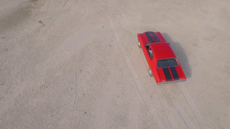 from the top view of an old american muscle car in a dirt road during a sunset