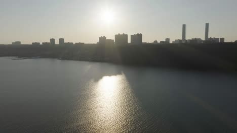 Aerial-view-towards-sunset-above-the-silhouette-skyline-of-Edgewater,-New-Jersey