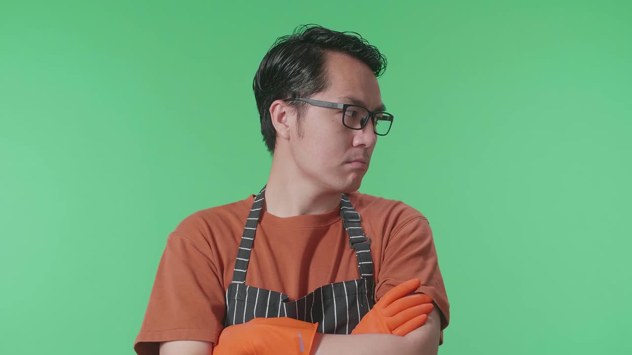 화려한 스크린 스튜디오에 서 있는 동안 팔을 고 주위를 둘러보는 아시안 남성 집사.