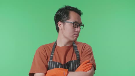 화려한 스크린 스튜디오에 서 있는 동안 팔을 고 주위를 둘러보는 아시안 남성 집사.