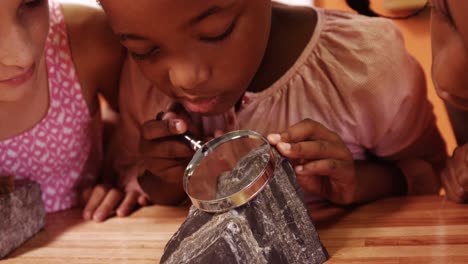 Niños-De-Escuela-Usando-Lupa-Sobre-Roca