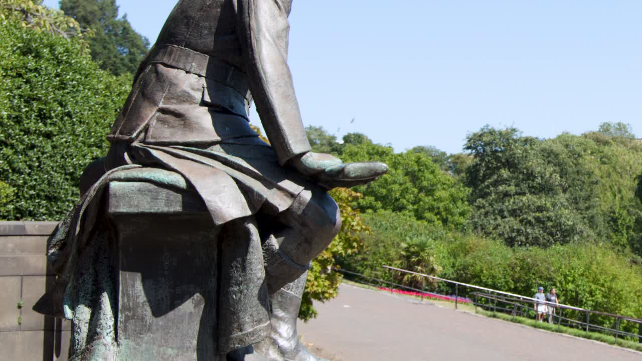 Side view of bronze statue as person walks by, sunny daylight, smooth lateral camera movement