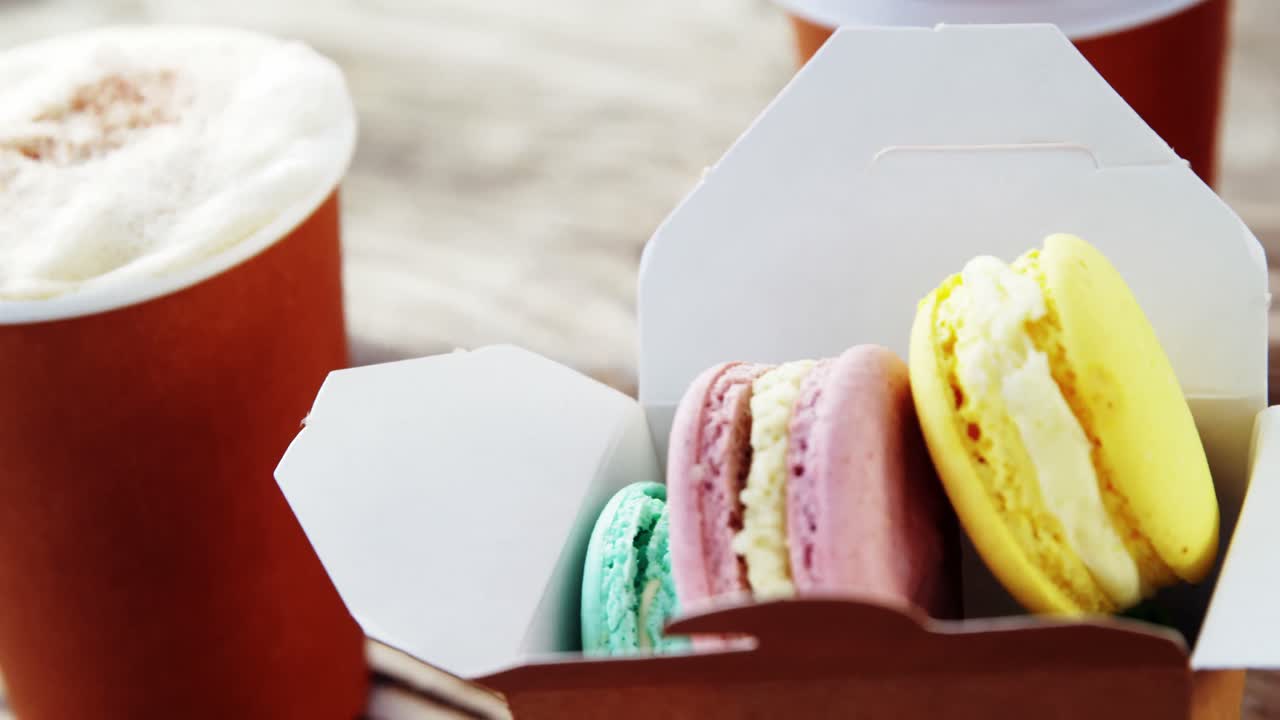 galletas de macarrón coloridas en una bolsa de papel con café