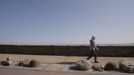 sitting bench and people walking on coastal pathway in san sebastian